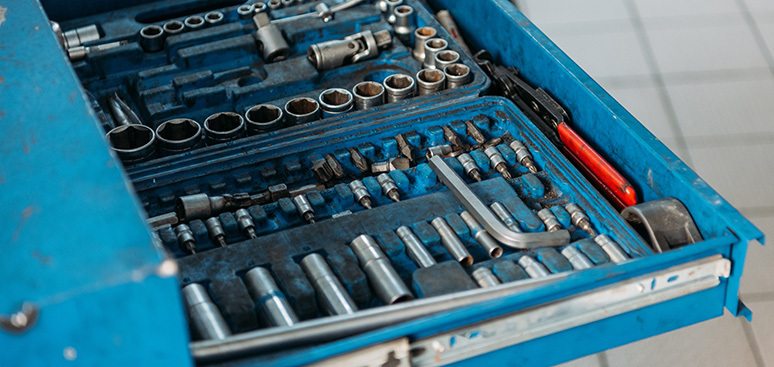 Open blue drawer filled with neatly organized mechanics' tools, including socket wrenches, screwdrivers, and hex keys, conveying a sense of order.